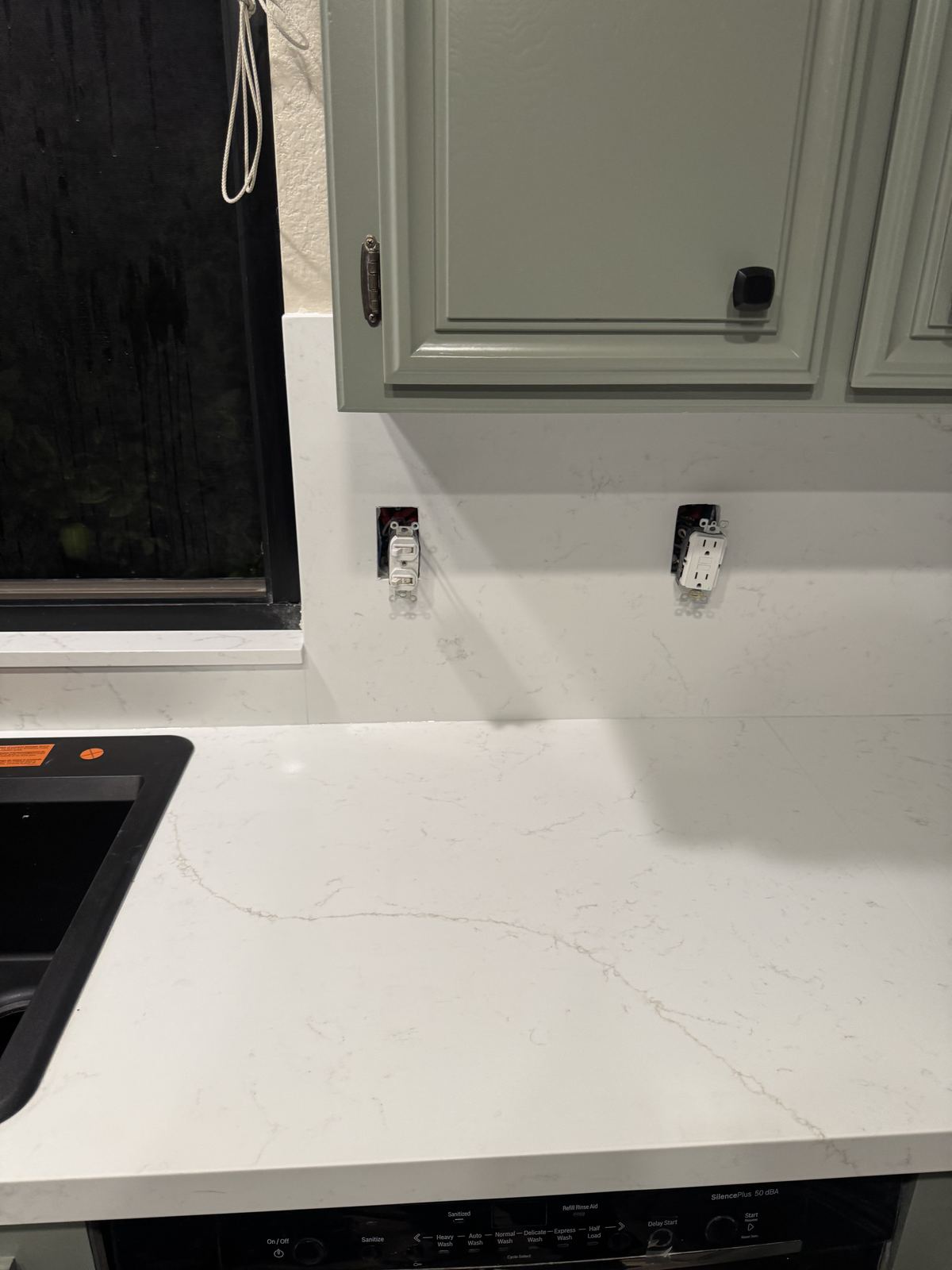Quartz backsplash detail with outlet cutouts — kitchen countertop installation